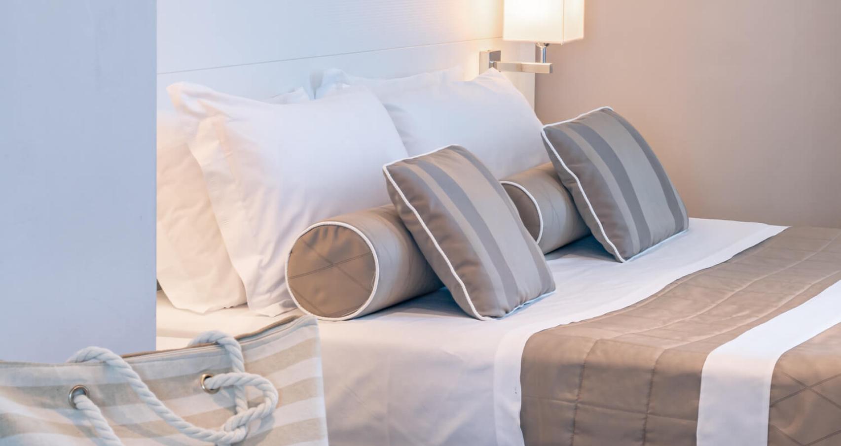 Camera da letto moderna con cuscini a righe e lampada da comodino.