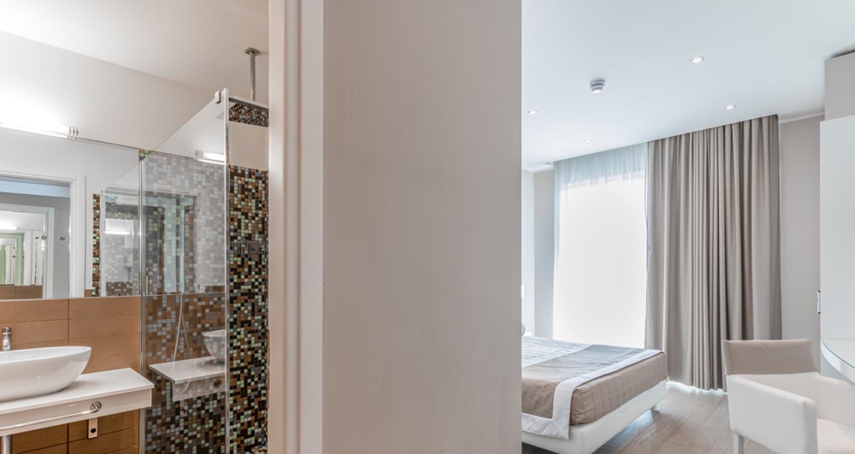 Bagno moderno con mosaico, lavabo elegante e asciugamani bianchi.