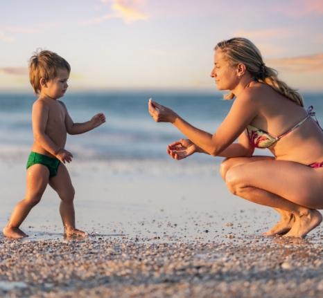 Madre e figlio giocano insieme sulla spiaggia al tramonto.