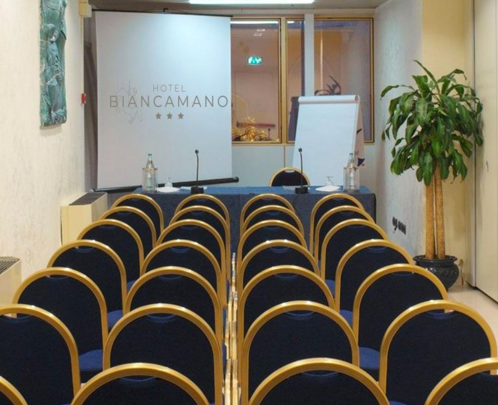 Sala conferenze dell'Hotel Biancamano con sedie e podio.