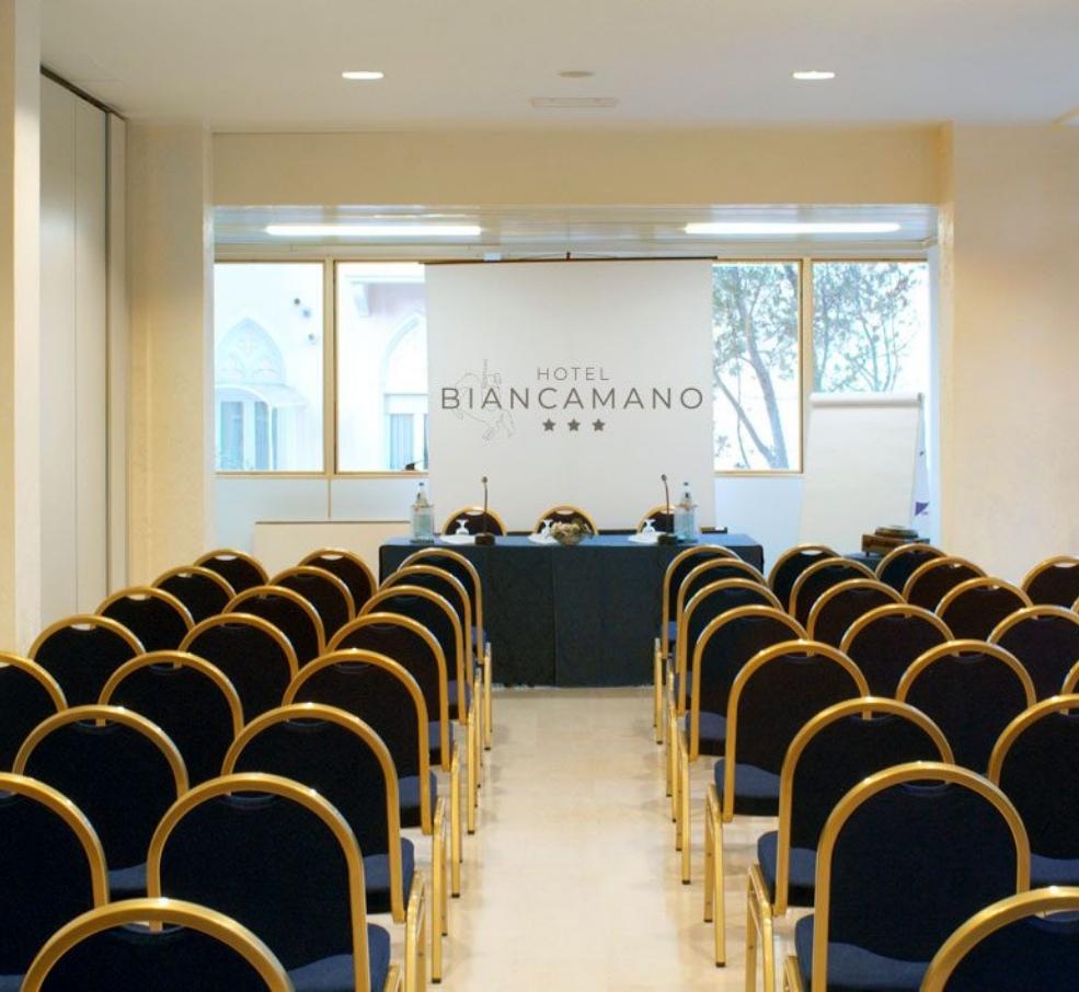 Conference room at Hotel Biancamano with aligned chairs and a speakers' table.