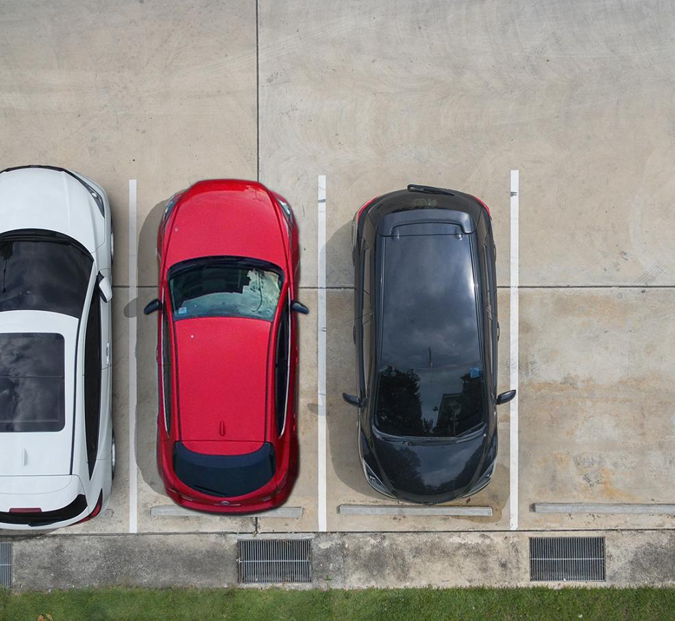 Three cars parked in a lot, viewed from above: white, red, and black.
